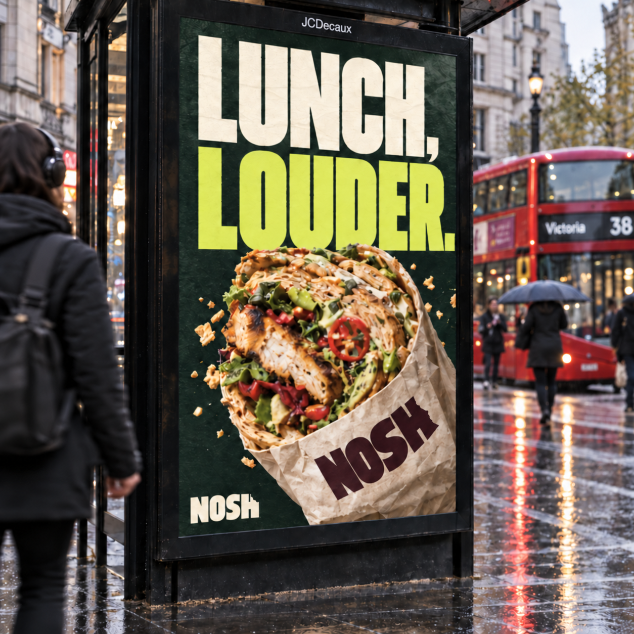 Bus shelter ad reading Lunch, Louder. with a torn-open Nosh sandwich pack, a red London bus passing behind