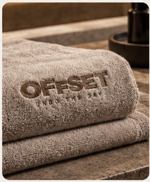Folded Offset-embroidered towels stacked on a stone bench